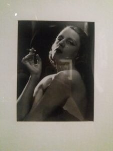 Zdjęcie czarno-białe będące portretem kobiety trzymającej papierosa w prawej dłoni
