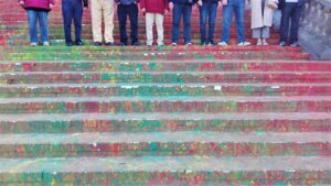 Dziesięć par nóg ludzkich stojących na schodach pomalowanych w kolorowe plamy