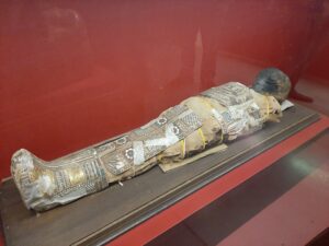 Starożytna mumia 8-letniego chłopca na czerwonym tle