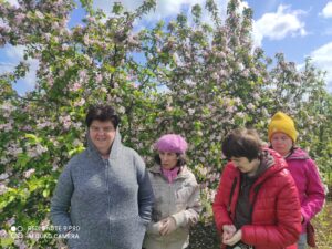 Cztery osoby stojące na tle kwitnących drzew owocowych