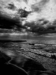 Fale na morzu i widoczny kawałek piaskowego brzegu oraz pochmurne niebo
