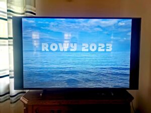 Ekran telewizora z wyświetlonym zdjęciem morza i napisem ROWY 2023 