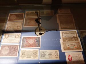 Zabytkowe papierowe pieniądze eksponowane w gablocie na niebieskim materiale
