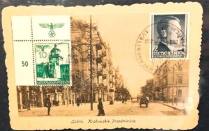 Czarno-biała pocztówka z ulicą dawnego Lublina oklejona znaczkami i z pieczęciami w języku niemieckim