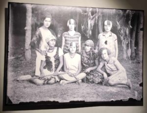 Czarno-biały szklany negatyw przedstawiający siedem młodych osób w strojach z okresu początku XX wieku
