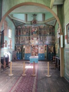 Wnętrze fragmentu grekokatolickiej cerkwi z ikonostasem i drewnianymi ścianami pomalowanymi na zielono