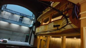 Wnętrze starego teatru z odsłoniętą sceną i dwoma poziomami balkonów na kolumnach