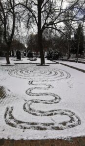 Geometryczne kształty wydeptane butami na śniegu a w tle widoczne ogrodzenie i drzewa