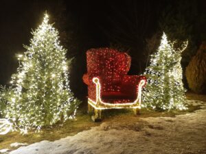 Przestrzenna iluminacja świetlna przedstawiająca czerwony duży fotel i dwie zielone choinki po jego bokach