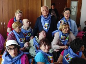 Grupa stojących dziesięciu dorosłych osób z kolorowymi chustami na szyi