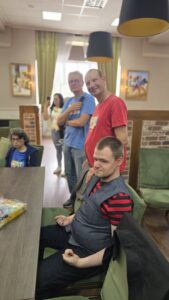 Grupa pięciu uśmiechniętych osób siedzących i stojących przy stole w sali
