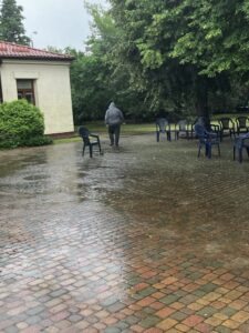 Mokra kostka brukowa z widoczną w oddali idącą postacią w szarej bluzie z kapturem