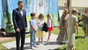 Troje dzieci i troje dorosłych stojących na tle kurtyny z namalowanymi drzewami