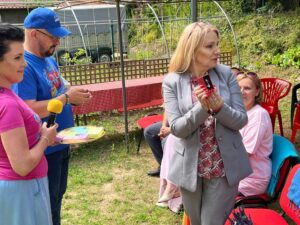 Trzy dorosłe osoby stojące na tle zieleni i pawilonu ogrodowego