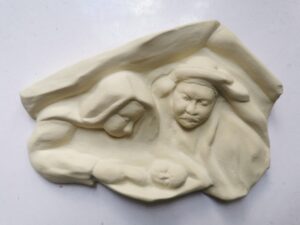 Odlew gipsowy w jasnożółtym kolorze przedstawiający Józefa i Marię trzymającą Jezusa jako niemowlę