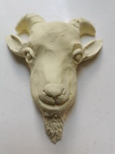 Odlew gipsowy w jasnożółtym kolorze przedstawiający głowę koziołka