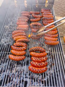 Widziany z góry duży prostokątny grill z ułożonymi wieloma kielbaskami