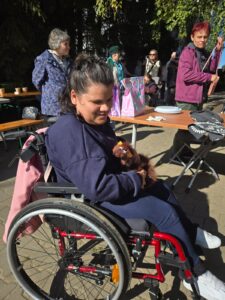 Uśmiechnięta kobieta w granatowym ubraniu dresowym siedząca na czerwonym wózku inwalidzkim