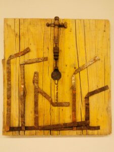 Collage z gotowych metalowych elementów przyczepionych do żółtej popękanej deski