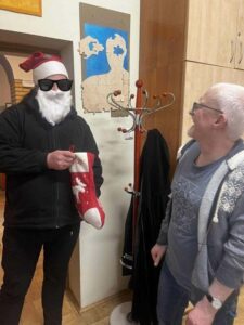 Dwóch mężczyzn w stojących w przestrzeni biurowej z czego jeden z nich przebrany jest za Mikołaja