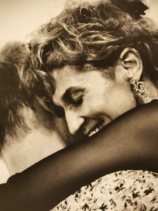 Fragment czarno-białej fotografii przedstawiający lewy profil twarzy kobiety przytulony do głowy mężczyzny