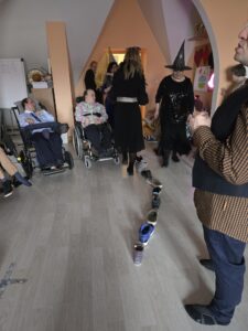 Grupa dorosłych osób we wnętrzu i ustawione przez środek sali buty w dużej ilości