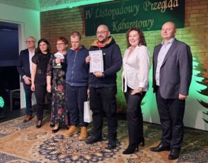 Siedem osób dorosłych stojących na scenie oświetlonej zielonym światłem