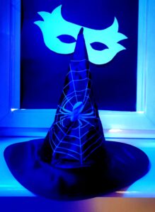 Szpiczasty kapelusz z wzorem pająka i pajęczyny na tle białej maski