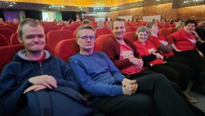 Widok sali widowiskowej i liczne dorosłe osoby siedzące w czerwonych fotelach