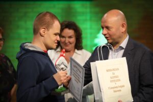 Widzianych z boku dwóch mężczyzn trzymających w rękach upominek i okolicznościowy dyplom