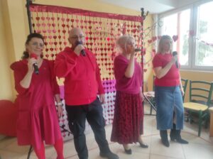 Grupa czterech osób w czerwonych ubraniach stojących we wnętrzu