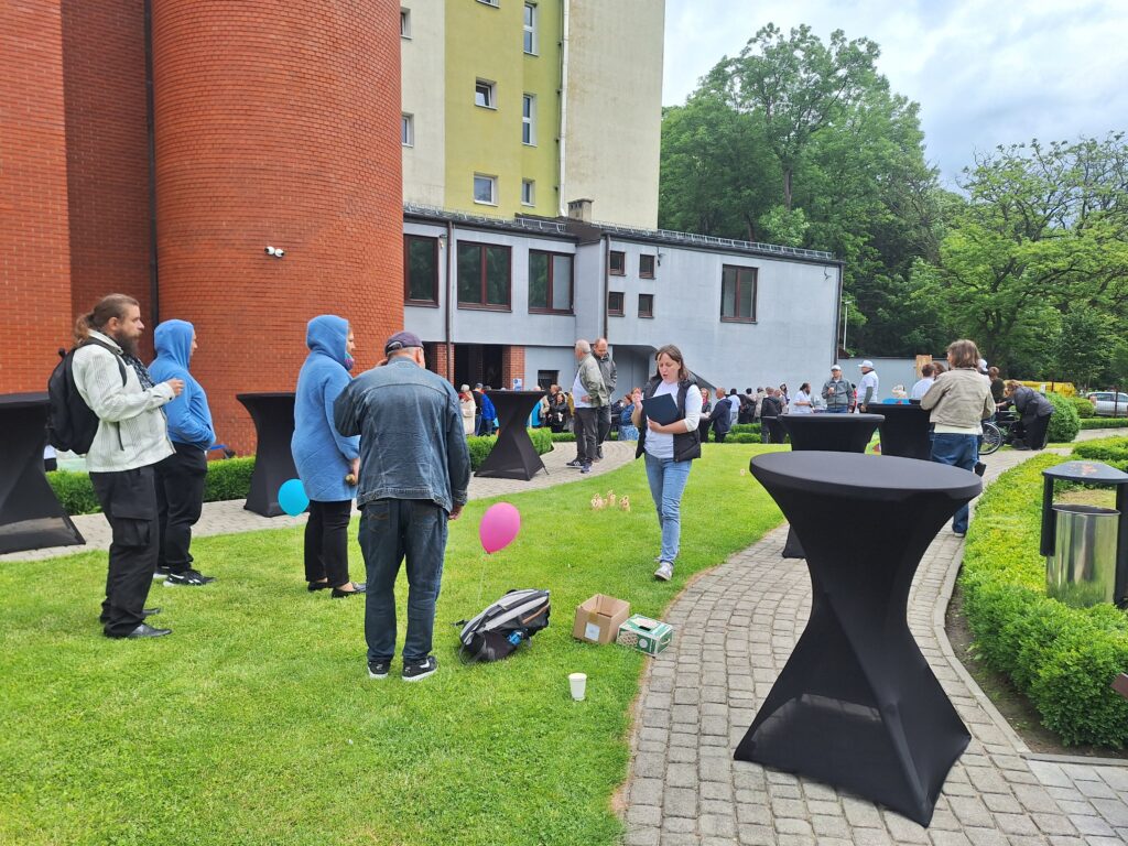 Grupa dorosłych osób grających w grę zręcznościową z rzutkami na trawniku