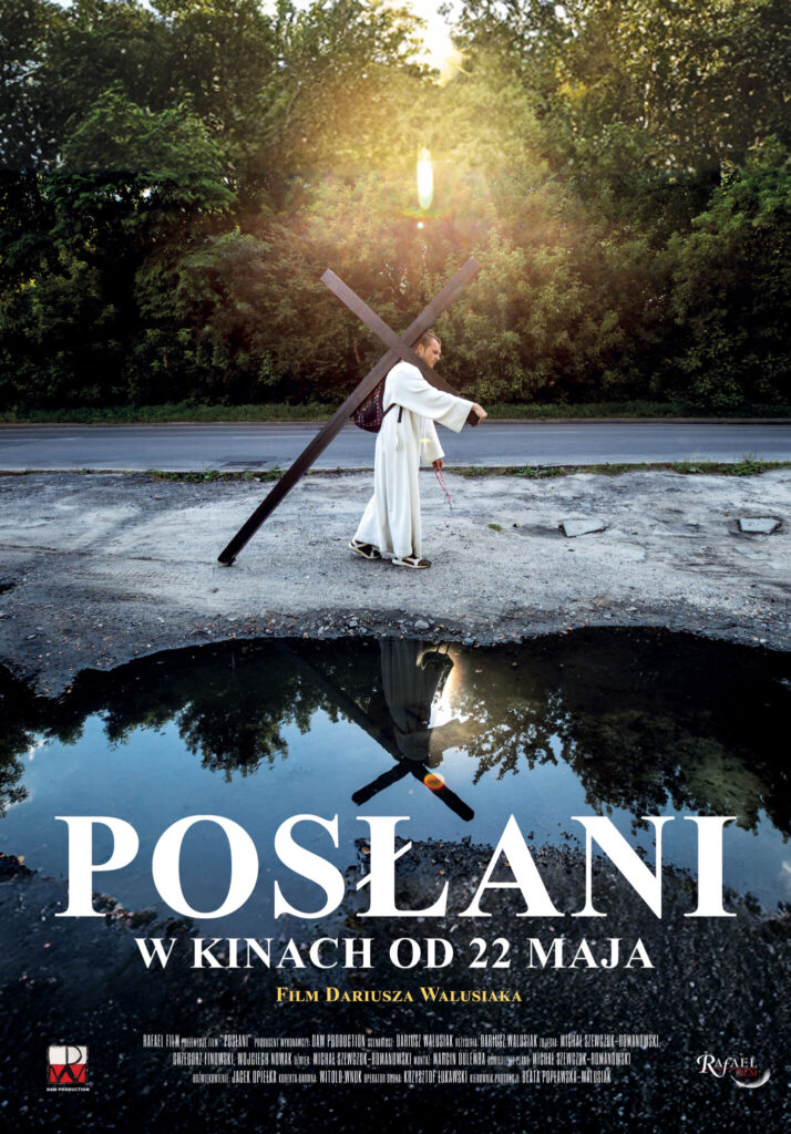 Plakat do filmu Posłani przedstawiający mężczyznę białym stroju niosącego duży krzyż na ramieniu a jednocześnie jego postać odbija się w wodzie na pierwszym planie