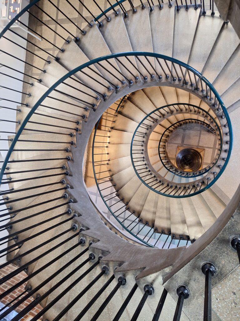 Okrągła kamienna klatka schodowa z metalową poręczą widziana z góry