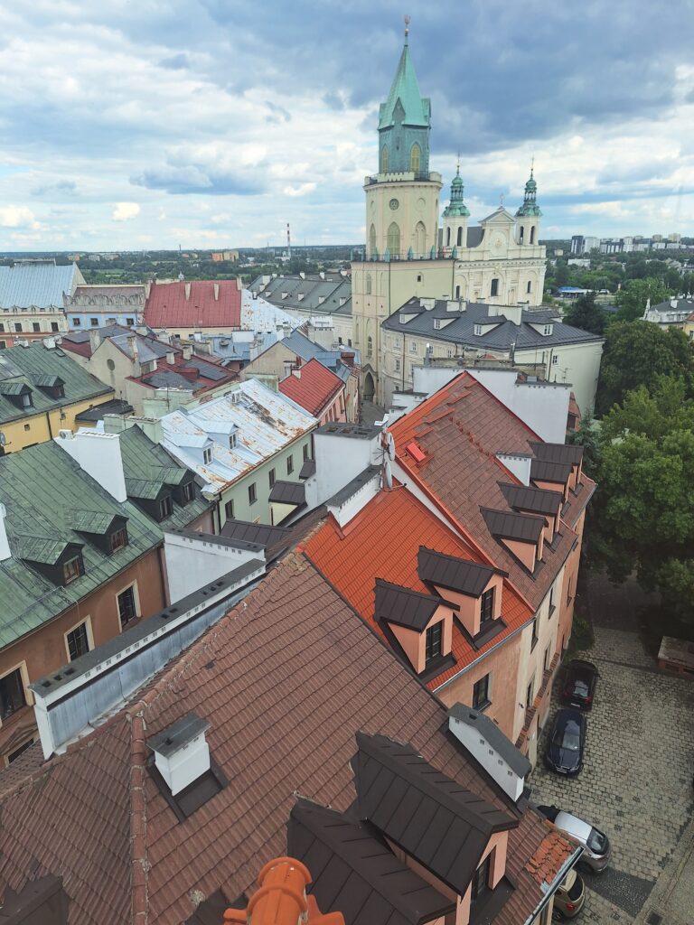 Pomarańczowe dachy kamienic widoczne z góry wieżą oraz budynek katedry stanowiące fragment zabudowy Starego Miasta w Lublinie