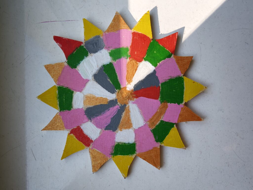 Forma ze sklejki wyciętej w kształcie kwiatu i pomalowana kolorowymi farbami w geometryczne wzory